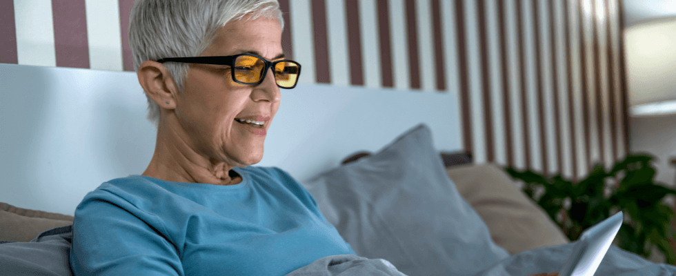 Femme avec lunettes anti-lumières bleue lisant du contenu sur sa tablette